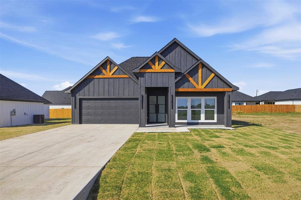 101 Connor Circle, Mabank, TX 75147 Modern farmhouse exterior featuring dark vertical siding, wood-toned gable accents, a multi-gabled roofline, and a concrete driveway