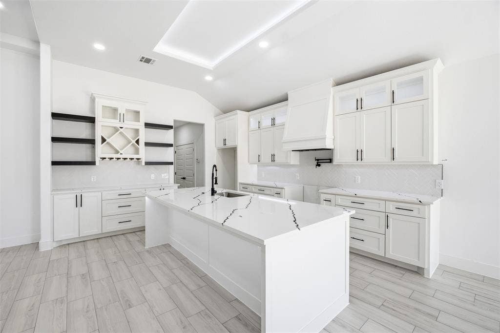 101 Connor Circle, Mabank, TX 75147 Kitchen featuring white shaker cabinetry, a waterfall-edge center island with stone-patterned surfacing, integrated wine storage, a farmhouse-style range hood, and wood-finish flooring