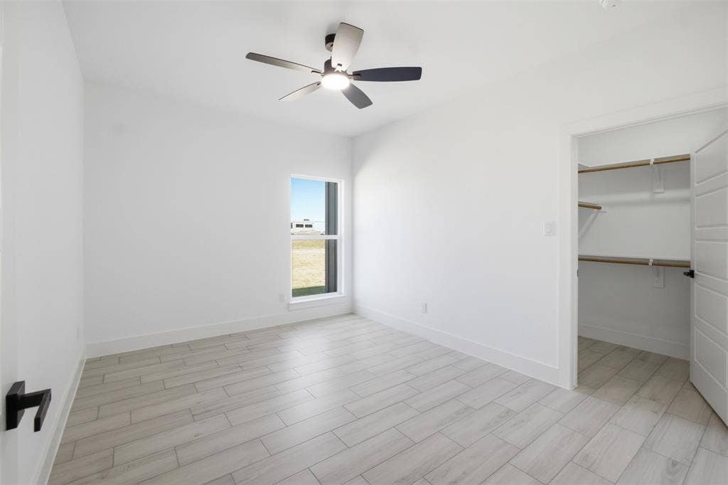 101 Connor Circle, Mabank, TX 75147 Wood-finish tile flooring, ceiling-mounted light fixture with fan, single-pane window, and walk-in closet with built-in shelving