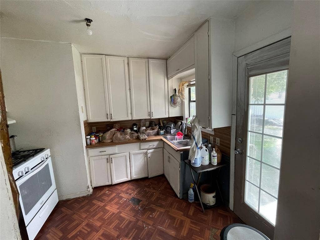 1115 Pine Street, Grand Prairie, TX 75050 Kitchen featuring white cabinetry, wood-finish parquet flooring, a stainless steel double-basin sink, and a glass-paneled exterior door