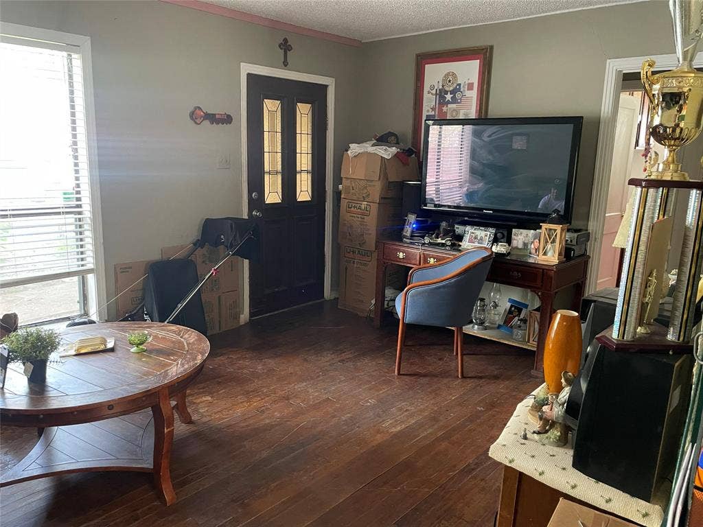 1115 Pine Street, Grand Prairie, TX 75050 Dark-toned wood-finish flooring, large window with horizontal blinds, and front door with decorative glass paneling