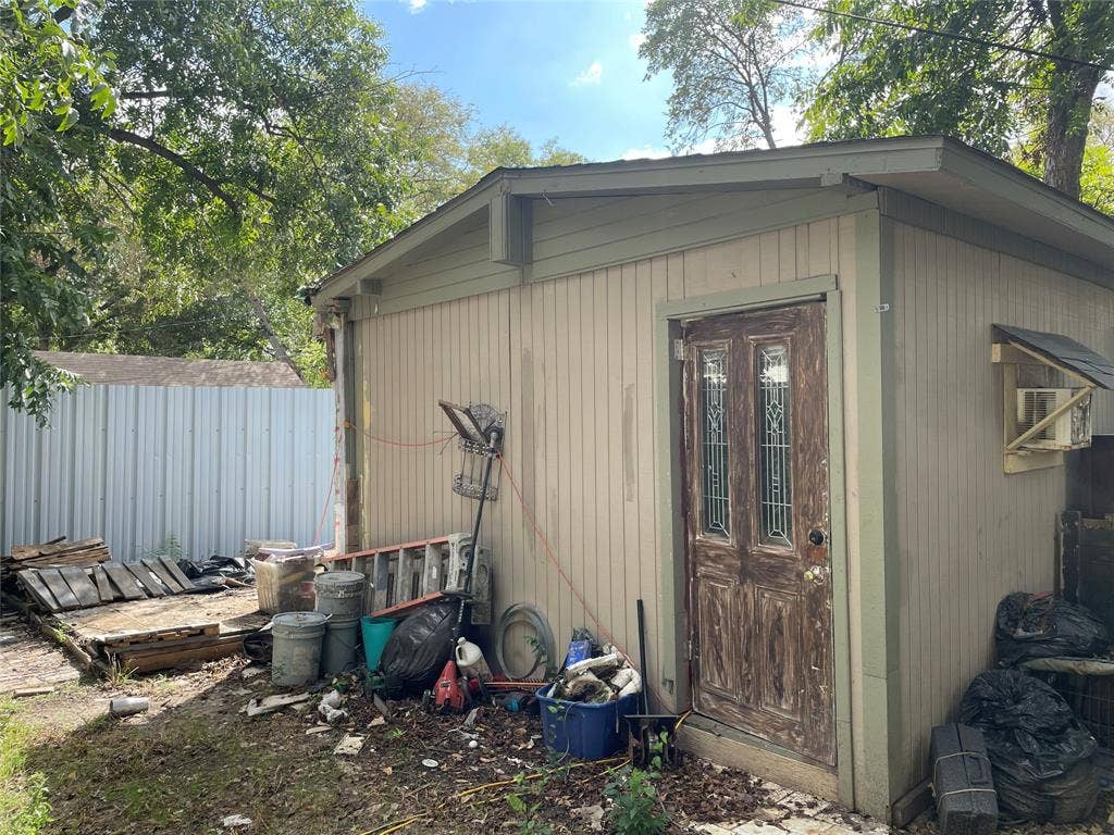 1115 Pine Street, Grand Prairie, TX 75050 Exterior structure with vertical wood siding and a door featuring glass panel inserts