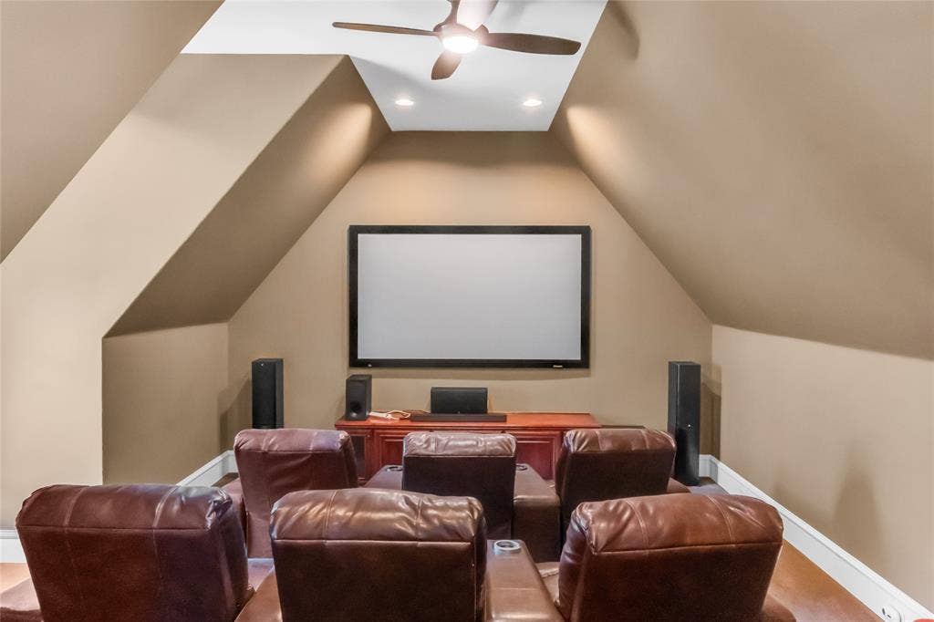 Vaulted ceilings with recessed lighting, an integrated ceiling fan, and a wall-mounted projection screen
