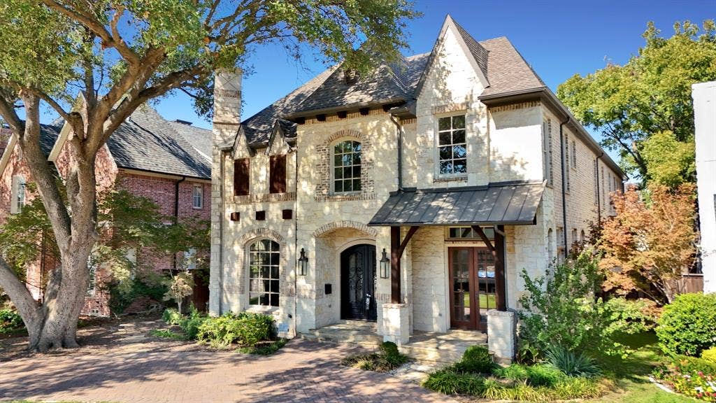 Traditional stone exterior featuring a multi-gabled roofline, metal awning, arched entryway, and multi-pane windows
