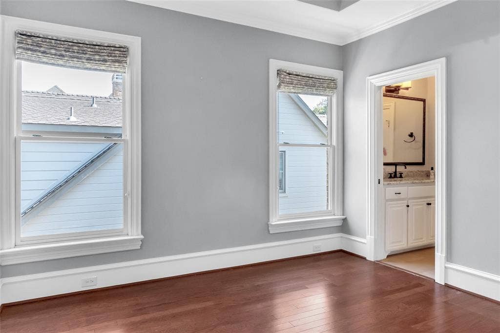 Interior space featuring wood-finish flooring, tall windows with crisp white casing, and crown molding
