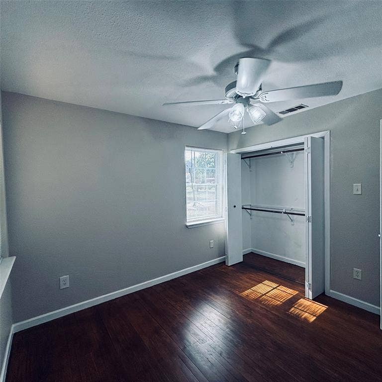 Room featuring wood-finish flooring, a multi-light ceiling fan, a window with muntins, and a closet with bifold doors