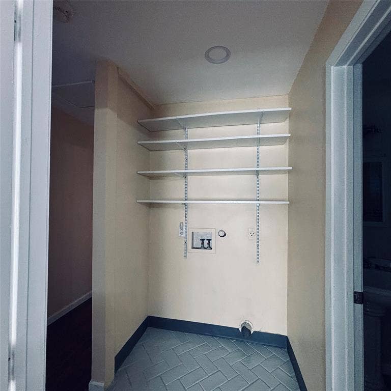 Utility space featuring herringbone-patterned tile flooring, integrated wall-mounted shelving, and recessed ceiling lighting