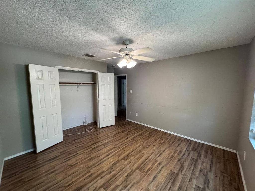 Room featuring wood-finish flooring, a ceiling fan with integrated lighting, and a closet with bifold doors