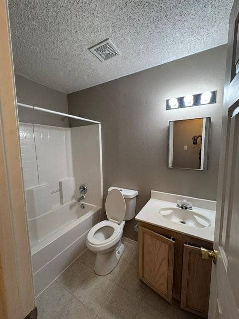 Bathroom featuring a tub-shower combination with white surrounds, a single-basin vanity with wood-finish cabinetry, a square frameless mirror, and a three-bulb wall-mounted vanity light fixture