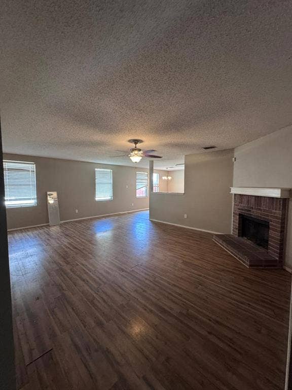 Living area featuring wood-finish flooring, brick fireplace with mantel, ceiling fan, and multiple windows