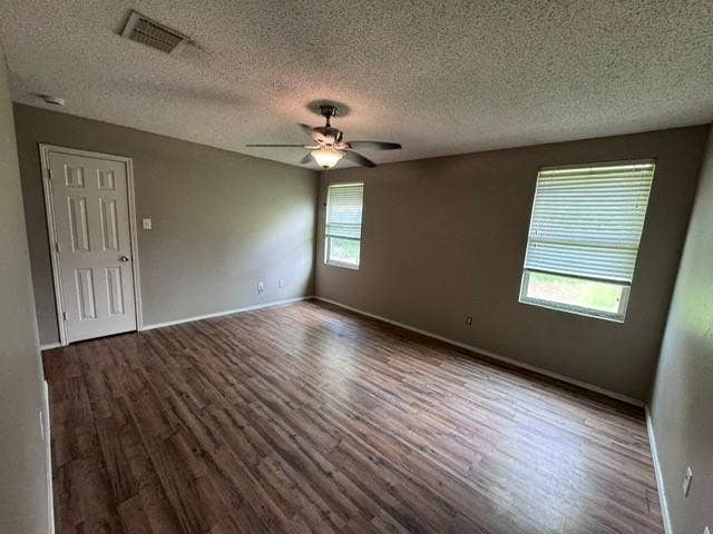 Interior room featuring wood-finish flooring, neutral wall paint, multi-pane windows with horizontal blinds, and a central ceiling fan with integrated lighting