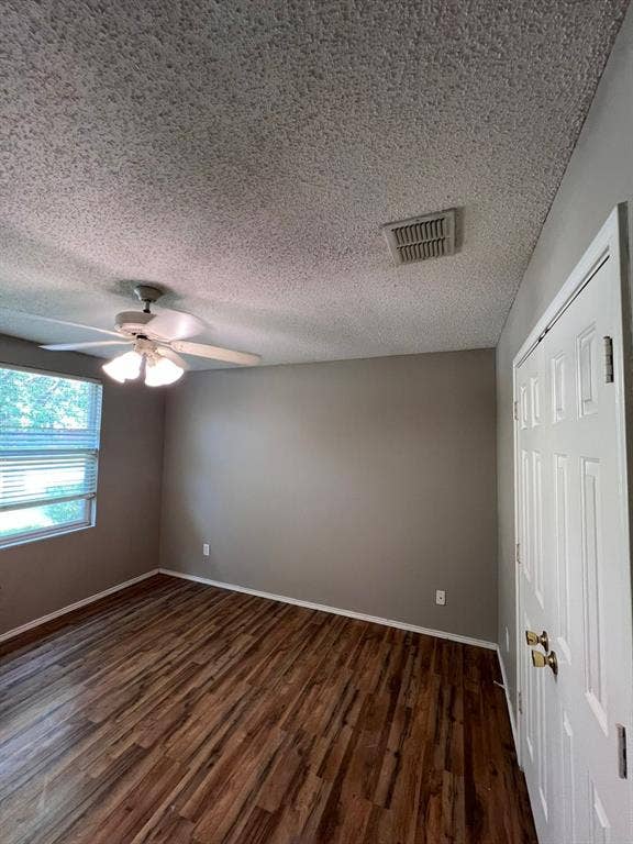 Wood-finish flooring, white paneled door with brass hardware, white ceiling fan with integrated light fixture, and horizontal blind window treatment