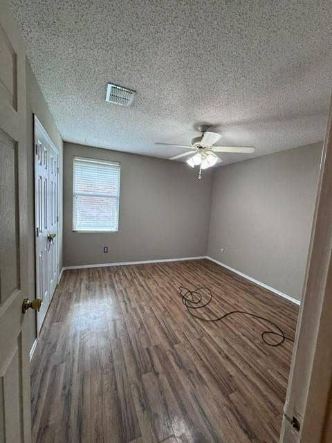 Interior room featuring wood-finish flooring, neutral wall paint, a ceiling fan with integrated lighting, and a double-door closet