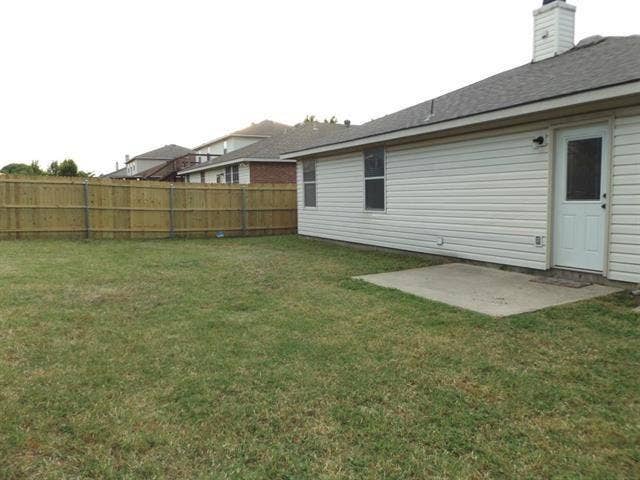 Backyard featuring a concrete patio, wood privacy fencing, and vinyl siding