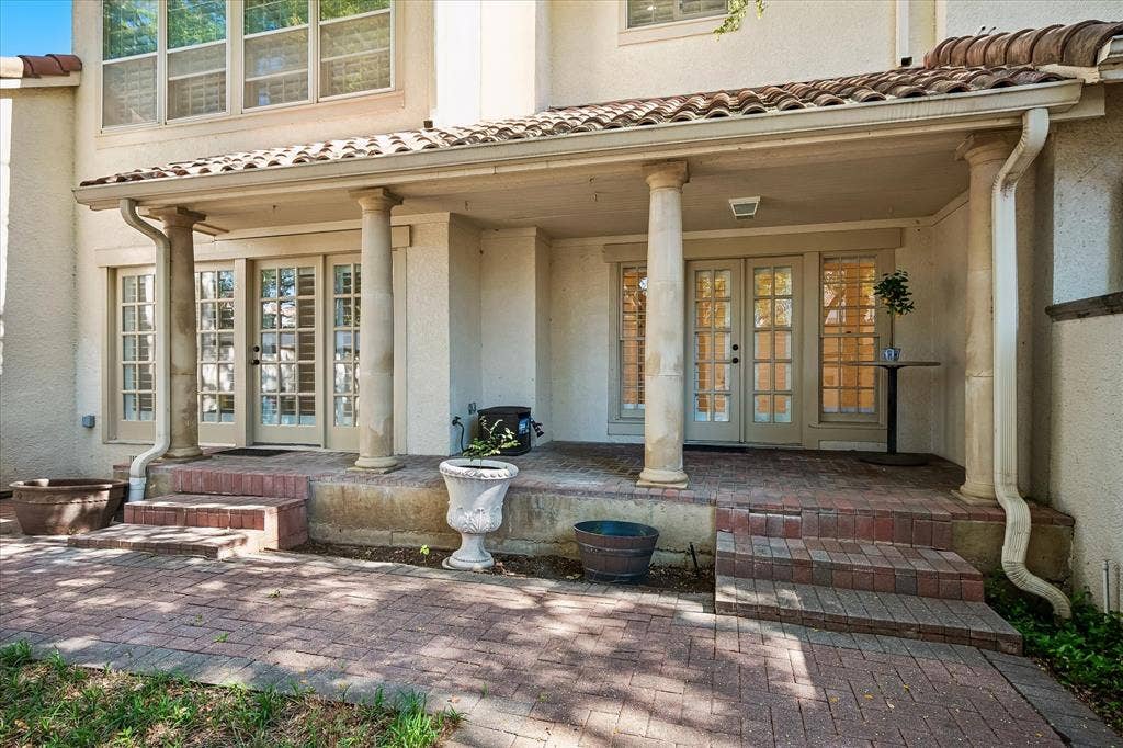 4611 O Connor Court, Irving, TX 75062 Covered patio featuring classical columns, terracotta tile roofing, multi-pane glass French doors, and patterned brick paving