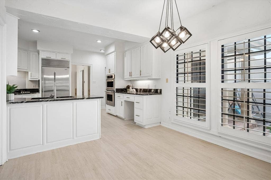 4611 O Connor Court, Irving, TX 75062 Kitchen featuring white cabinetry, dark stone countertops, stainless steel appliances including a built-in double oven and refrigerator, wood-finish flooring, and geometric pendant lighting