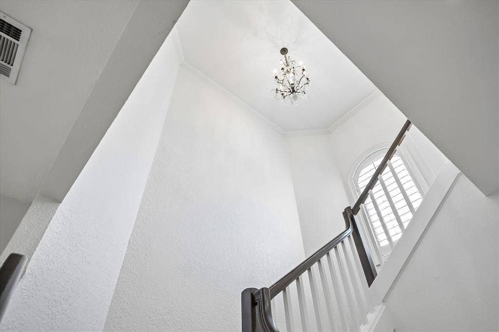 4611 O Connor Court, Irving, TX 75062 High-ceilinged entry featuring a tiered crystal chandelier, arched window with plantation shutters, and a staircase with white vertical balusters and a dark wood handrail