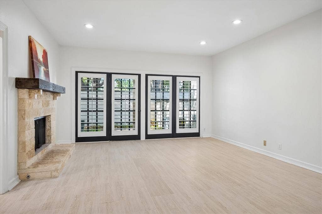 4611 O Connor Court, Irving, TX 75062 Fireplace with natural stone surround and timber mantel, wood-finish flooring, recessed lighting, and double-paned French doors with grid detailing