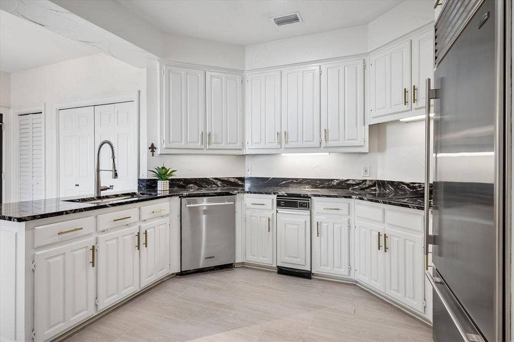 4611 O Connor Court, Irving, TX 75062 Kitchen featuring white shaker-style cabinetry, dark stone countertops with contrasting veining, stainless steel appliances, a high-arc pull-down faucet, and light-toned tile flooring