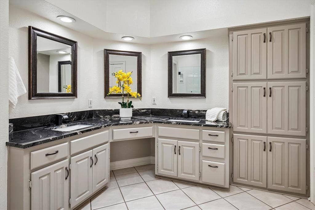4611 O Connor Court, Irving, TX 75062 Dual-sink vanity with dark stone countertop, inset rectangular basins, recessed lighting, and extensive built-in floor-to-ceiling cabinetry