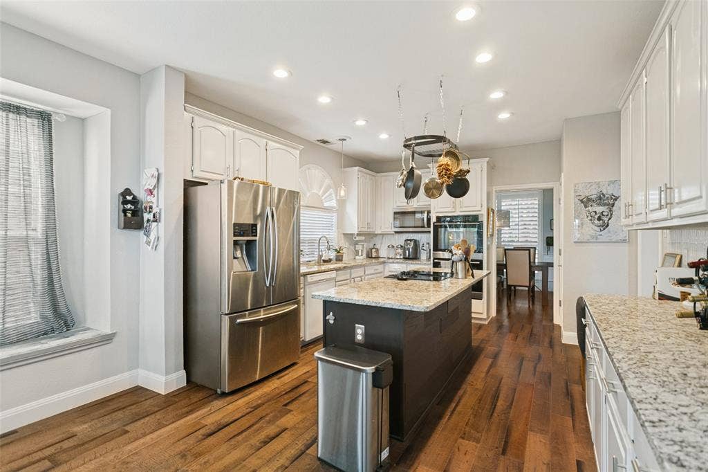 3212 Chippenham Drive, Plano, TX 75093 Kitchen featuring wood-finish flooring, white cabinetry, a center island with a stone-finish countertop, stainless steel appliances, and recessed lighting