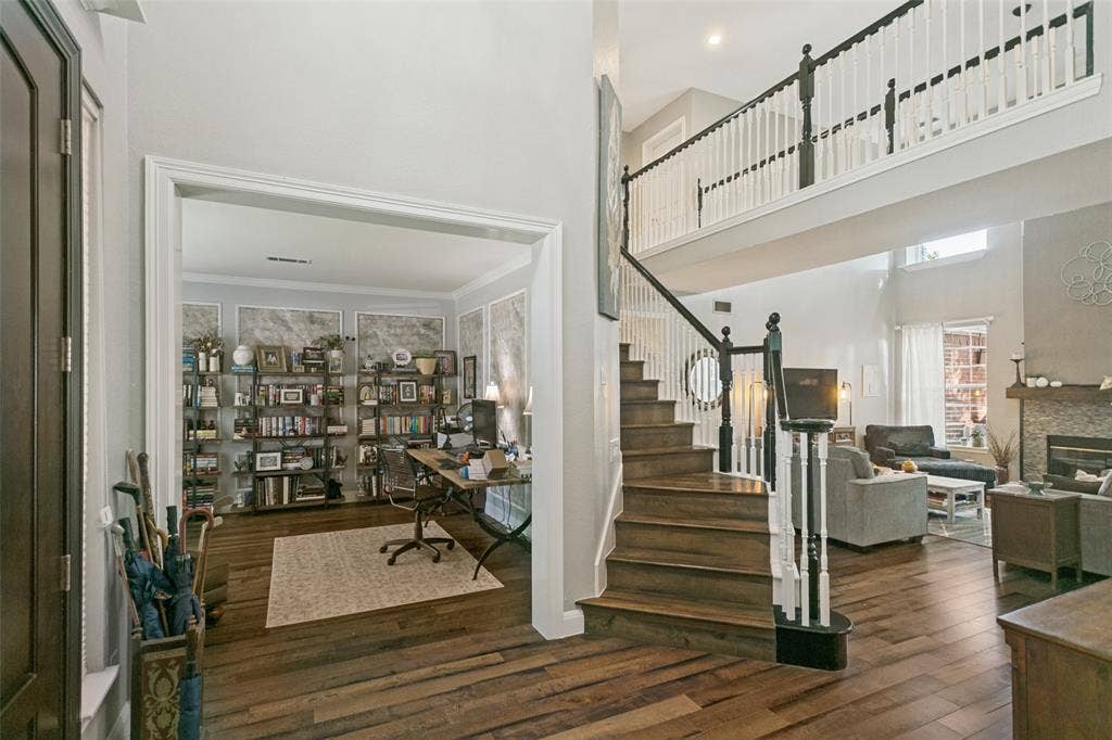 3212 Chippenham Drive, Plano, TX 75093 Two-story foyer featuring high ceilings, wood-finish flooring, a wood-tread staircase with white railings, and a stone-surround fireplace