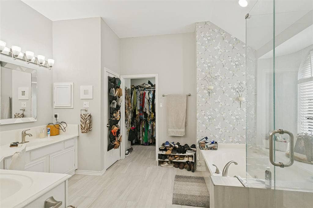 3212 Chippenham Drive, Plano, TX 75093 Bathroom featuring a dual-sink vanity with white cabinetry, a glass-enclosed shower, a deep soaking tub, and ceramic tile flooring