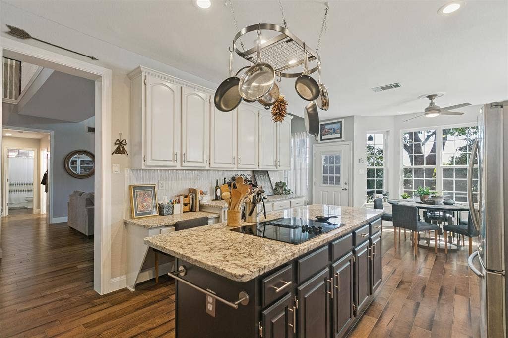 3212 Chippenham Drive, Plano, TX 75093 Kitchen featuring stone-topped island with a built-in cooktop, overhead pot rack, white cabinetry, and wood-finish flooring