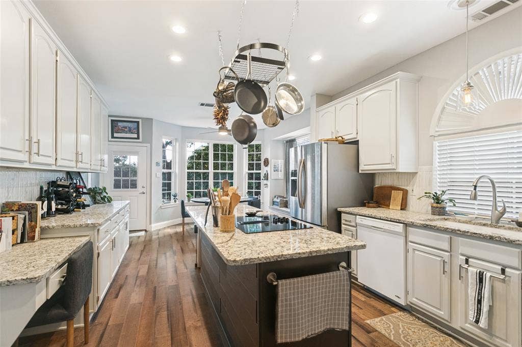 3212 Chippenham Drive, Plano, TX 75093 Kitchen featuring white shaker-style cabinetry, stone-finish countertops, a dark-toned center island with an integrated cooktop, recessed lighting, and wood-finish flooring