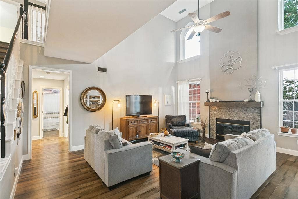 3212 Chippenham Drive, Plano, TX 75093 Living area featuring tall ceilings, a floor-to-ceiling fireplace with stone tile surround, wood-finish flooring, and arched windows