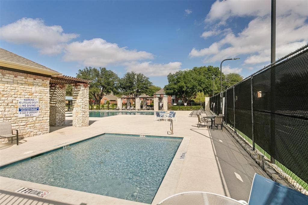 3212 Chippenham Drive, Plano, TX 75093 Swimming pool with stone-veneer accent wall, pergola-covered deck area, and enclosed tennis court