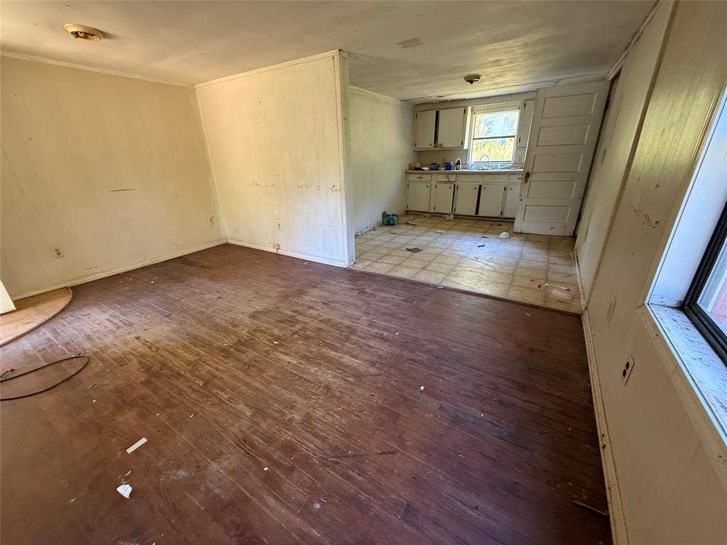 Interior area featuring wood-finish flooring, white cabinetry, a kitchen sink, and a multi-panel interior door