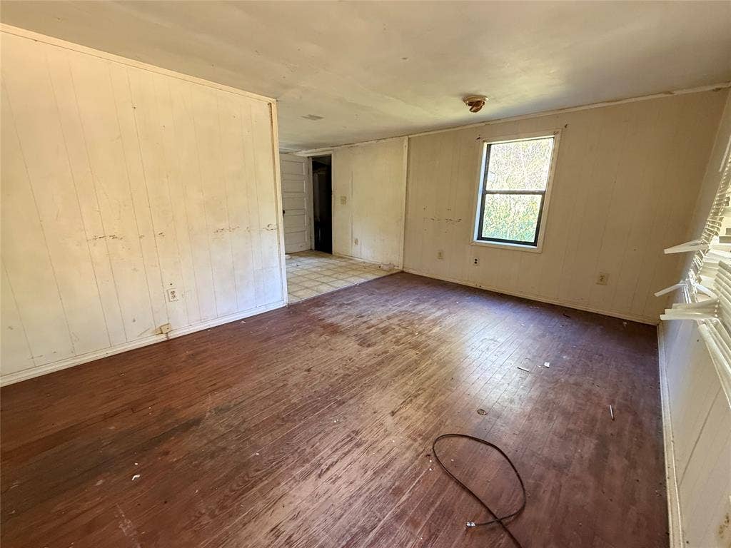 Interior room featuring wood-finish flooring, paneled walls, and a single-pane window