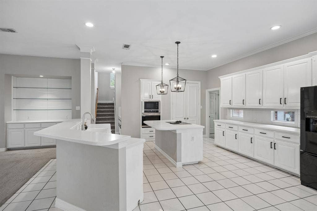 Kitchen featuring white cabinetry, center island with cooktop, built-in wall oven and microwave, ceramic tile flooring, and lantern-style pendant lighting
