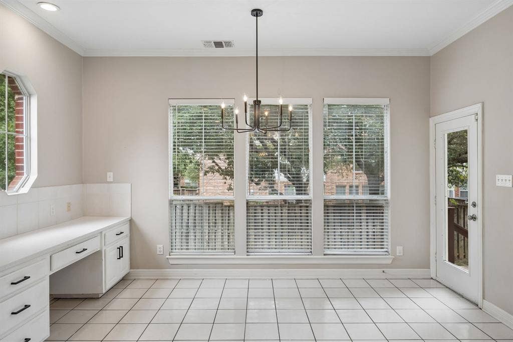 Room featuring tile flooring, built-in cabinetry with white countertops, a six-light chandelier, and large windows with horizontal blinds