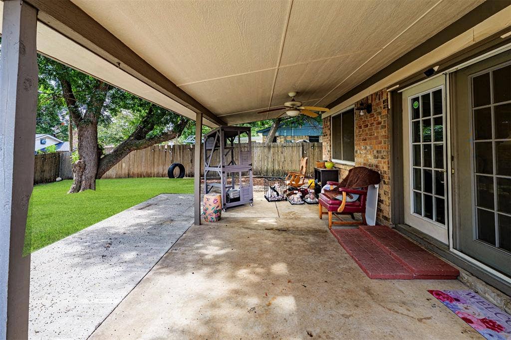 Covered concrete patio featuring a ceiling fan, brick exterior siding, and sliding glass door access