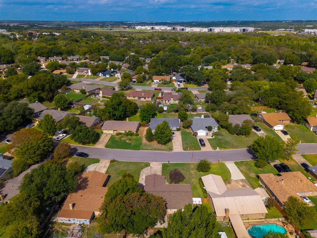 Aerial perspective of a suburban neighborhood featuring mature canopy trees, paved street infrastructure, and established landscaping