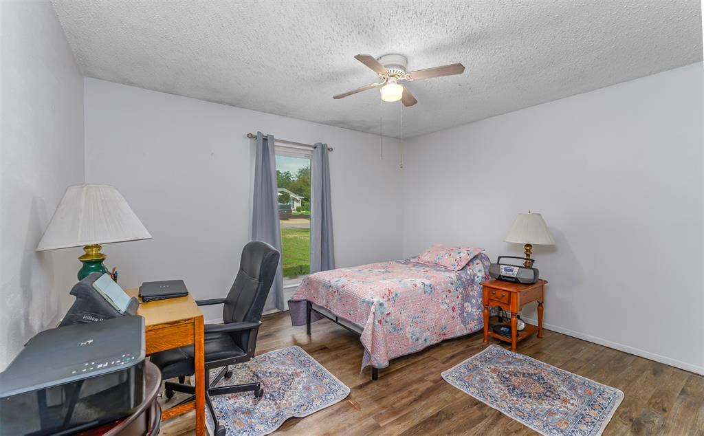 Wood-finish flooring, ceiling fan with integrated lighting, and a single-pane window