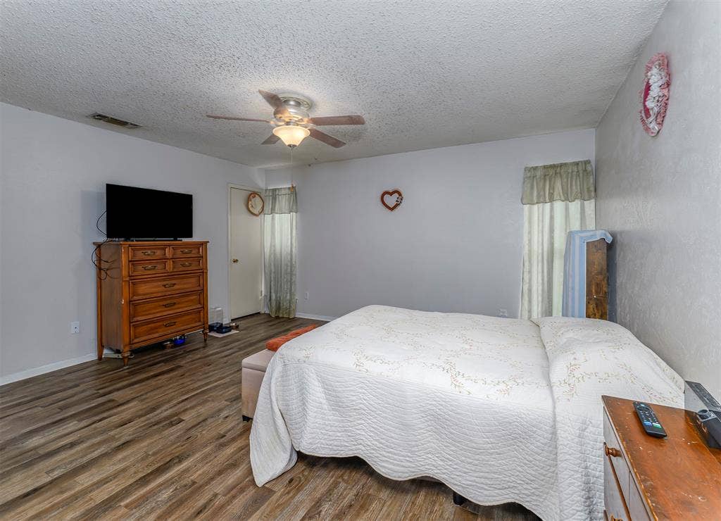 Wood-finish flooring, textured ceiling, and a ceiling-mounted light fixture with fan
