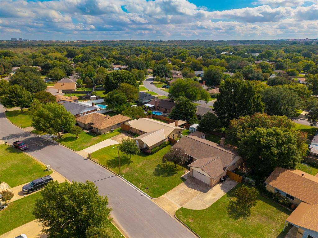 Aerial perspective featuring established residential landscaping, mature trees, and concrete driveways