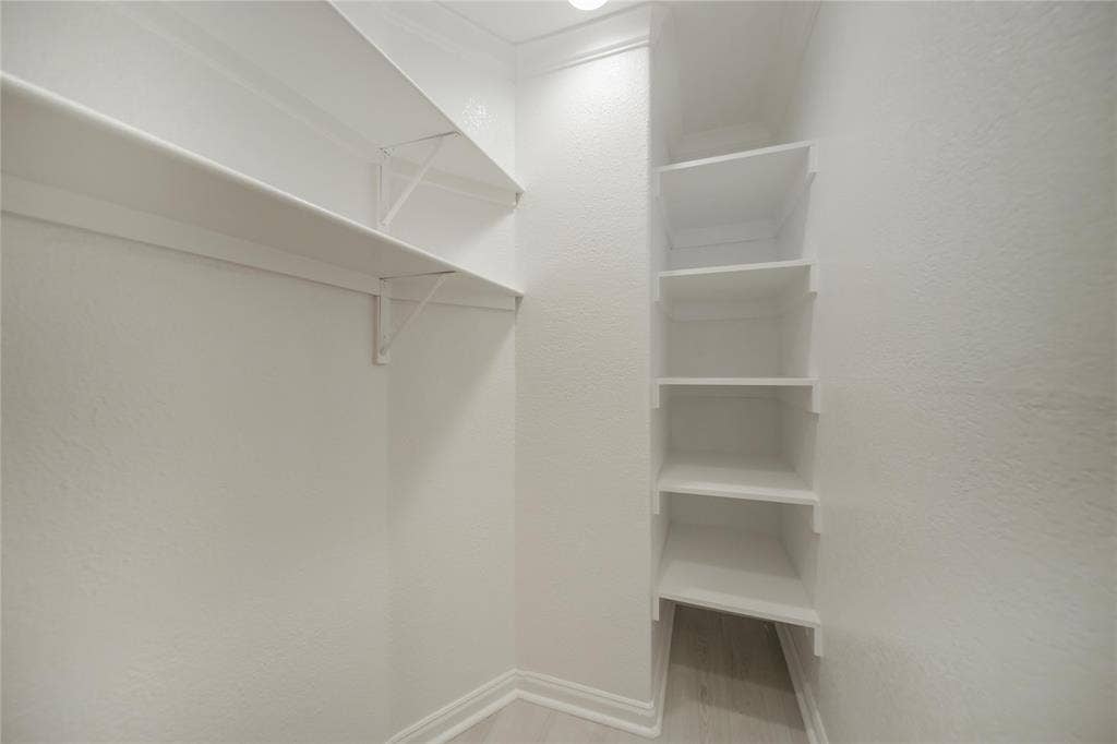 Custom storage space featuring multiple white-painted wooden shelves and a corner shelving unit with integrated wall-mounted brackets