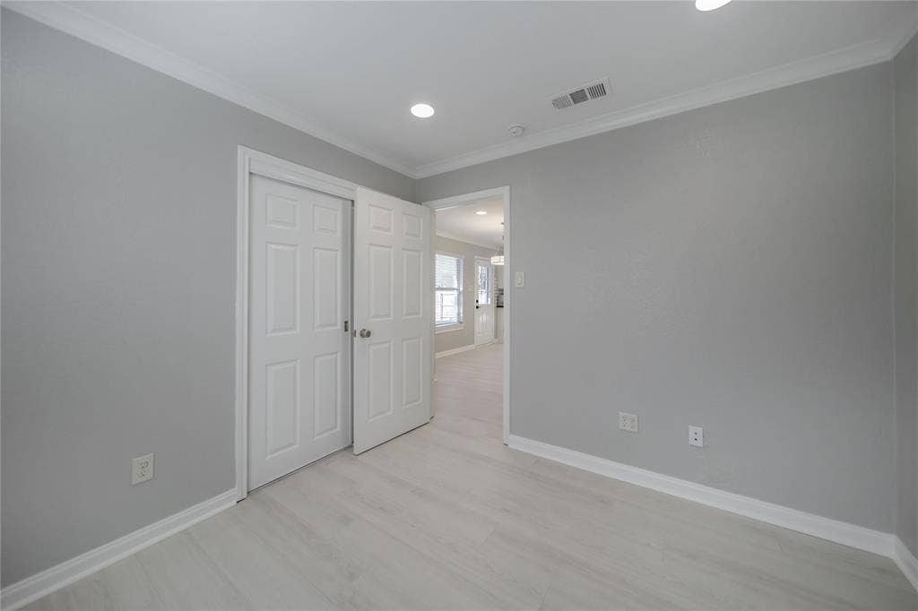 Neutral-toned interior room featuring wood-finish flooring, recessed lighting, and crown molding