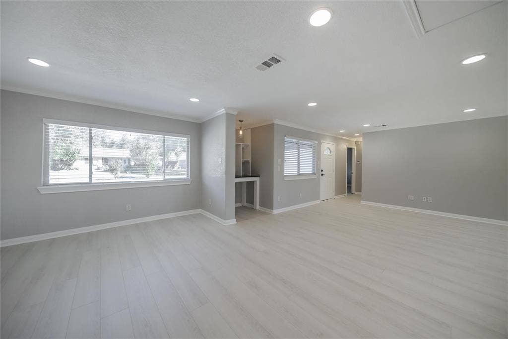 Interior space featuring wood-finish flooring, recessed lighting, neutral wall paint, and a built-in refreshment station with a stone countertop