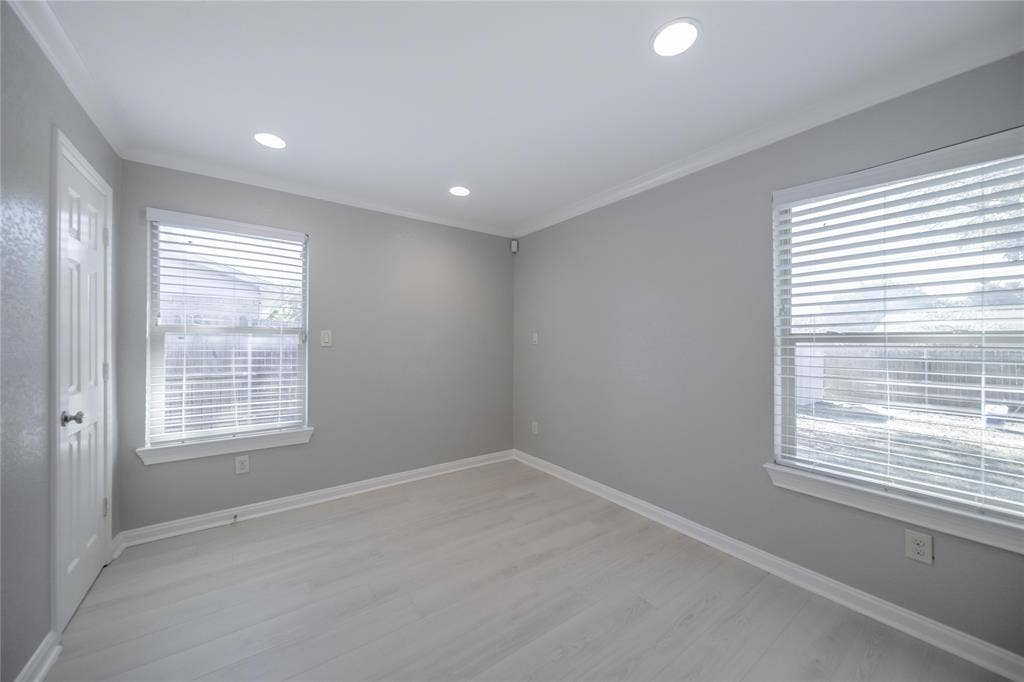 Interior space featuring light-toned wood-finish flooring, recessed lighting, neutral wall paint, and two windows with horizontal blinds