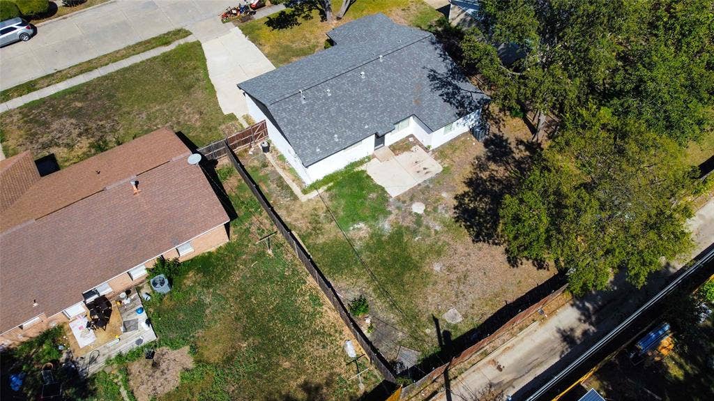 Exterior view featuring an asphalt shingle roof, white siding, concrete patio, and fenced backyard with mature trees