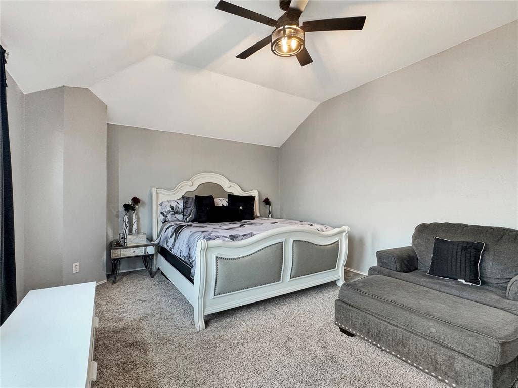 Vaulted ceiling with an integrated dark-finish ceiling fan and light fixture, complemented by neutral carpeting