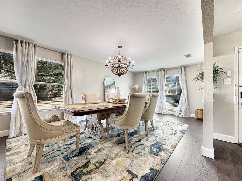 Dining area featuring wood-finish flooring, a decorative spherical chandelier, and multiple large windows