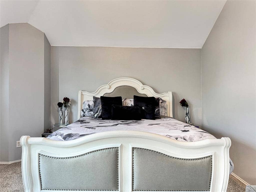 Neutral-toned walls featuring a vaulted ceiling and wall-to-wall carpeting
