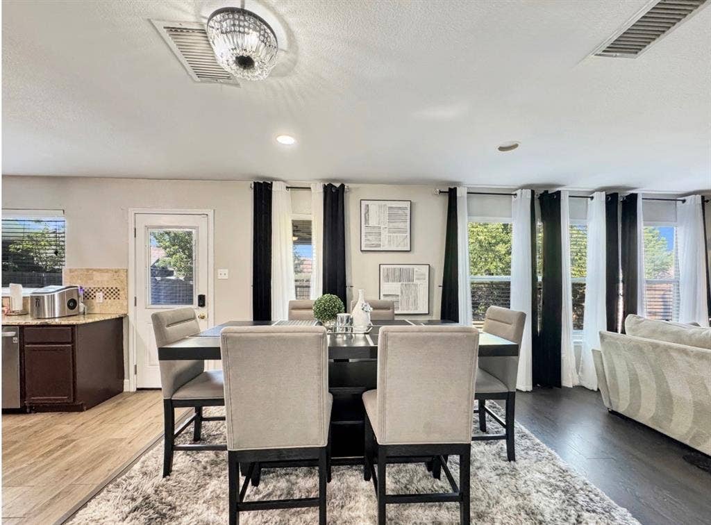 Open-concept interior featuring dark wood-finish flooring, a tiered crystal chandelier, and a neutral color palette