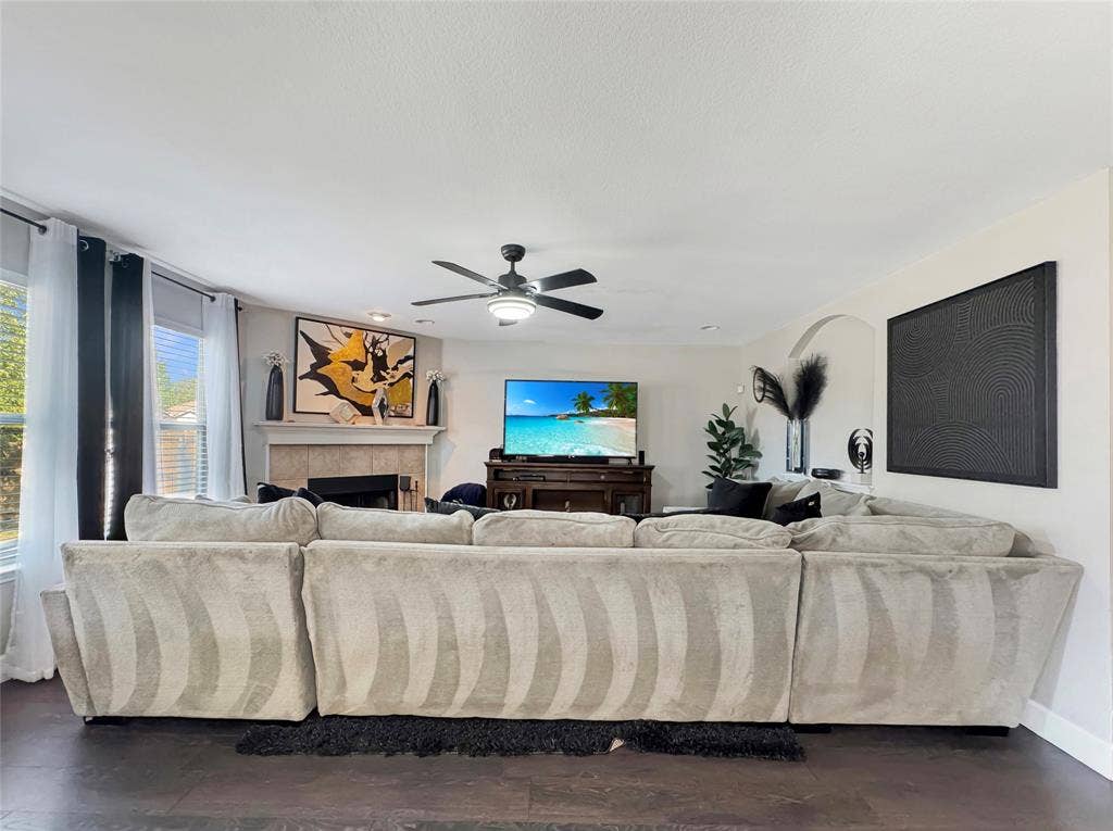 Living area featuring wood-finish flooring, a fireplace with a stone-finish surround, recessed lighting, and a multi-blade ceiling fan